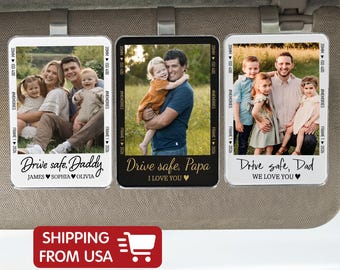 May include: Three car visor clips with family photos. Each clip has a different photo and message: "Drive safe, Daddy," "Drive safe, Papa," and "Drive safe, Dad." The clips have a black and white border with the text "#MEMORIES" and "FRAME 1 2026."