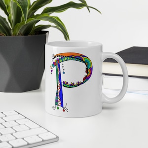 Può includere: Tazza in ceramica bianca con una lettera "P" artistica e colorata. La lettera è decorata con una varietà di colori e motivi, tra cui arancione, blu, verde e viola. La tazza ha un manico standard ed è adatta per bevande.
