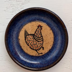 May include: A white ceramic mug with a black handle and the text "But First, Coffee" in a bold, black font. The mug is set against a blurred background, highlighting its clean design.