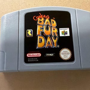 May include: A gray Nintendo 64 video game cartridge for Conker's Bad Fur Day. The black label features the game title in yellow and orange lettering, the Rare logo, the Nintendo 64 logo, the Nintendo logo, the THQ logo, and the Seal of Quality.