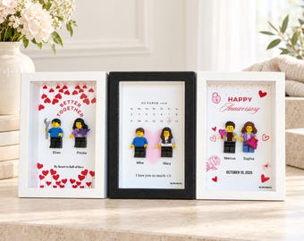 Może przedstawiać: Trzy prostokątne ramki typu shadow box z personalizowanymi minifigurkami. Lewa ramka zawiera czerwone serca i napis Better Together. Środkowa ramka przedstawia kalendarz na październik 2026 roku. Prawa ramka zawiera napis Happy Anniversary.