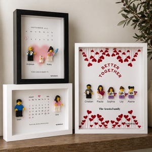 May include: Three rectangular shadow box frames containing custom displays. Two frames feature printed calendars with minifigures and names, while the third displays the text Better Together with five minifigures and red heart illustrations.