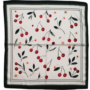 May include: A square scarf featuring a white background with a repeating pattern of red cherries, green leaves, and small white flowers. The scarf is framed by a thin dark green border and a wider black outer border, creating a distinct edge.