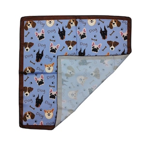 May include: A blue dog-themed blanket with a brown border. The blanket features various dog breeds, bones, and the word "Dog" in a repeating pattern. The reverse side has a lighter blue background with dog illustrations.