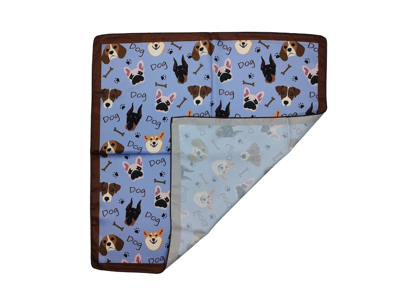 May include: A blue dog-themed blanket with a brown border. The blanket features various dog breeds, bones, and the word "Dog" in a repeating pattern. The reverse side has a lighter blue background with dog illustrations.