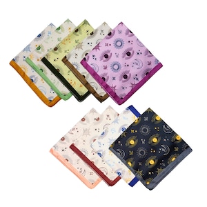 May include: A collection of square handkerchiefs with celestial eye, sun, and moon patterns. The handkerchiefs feature various color schemes, including gold, green, purple, and navy blue. Each handkerchief has a contrasting border.