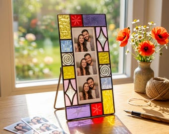 May include: A rectangular stained glass photo frame with a metal stand, featuring colorful glass tiles in yellow, purple, red, and light blue. The frame holds a vertical strip of three photographs showing a couple, with additional loose photo strips nearby.