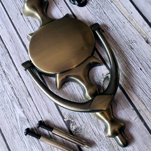 Puede incluir: Un llamador de puerta de lat&oacute;n con un dise&ntilde;o circular y un asa de anillo decorativo. Viene con dos tornillos para la instalaci&oacute;n.
