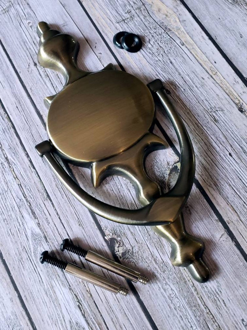 Puede incluir: Un llamador de puerta de lat&oacute;n con un dise&ntilde;o circular y un asa de anillo decorativo. Viene con dos tornillos para la instalaci&oacute;n.