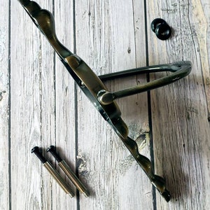 Puede incluir: Pomo de metal de estilo antiguo con un dise&ntilde;o decorativo. El pomo es de color bronce oscuro y tiene una forma curva. Se incluyen dos tornillos para la instalaci&oacute;n.