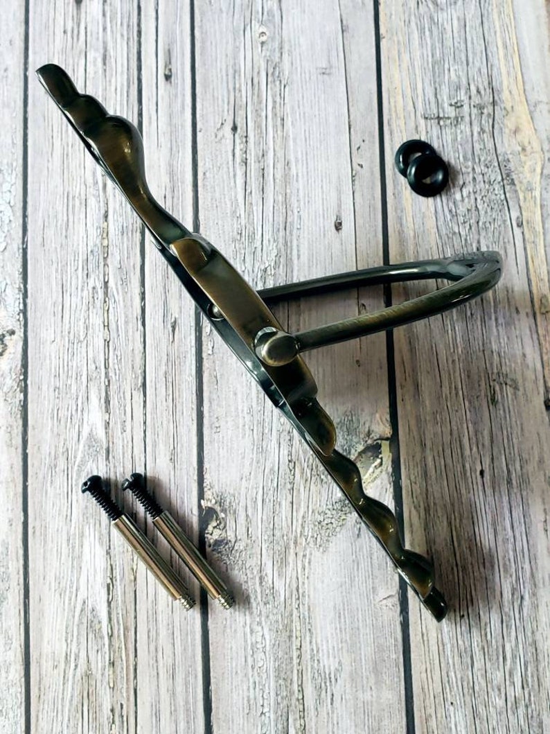 Puede incluir: Pomo de metal de estilo antiguo con un dise&ntilde;o decorativo. El pomo es de color bronce oscuro y tiene una forma curva. Se incluyen dos tornillos para la instalaci&oacute;n.