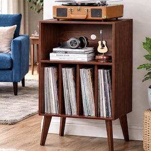 May include: A mid-century modern record player stand in dark brown wood. The stand has a built-in record player, storage for vinyl records, and a small decorative guitar. The stand is on wooden legs.