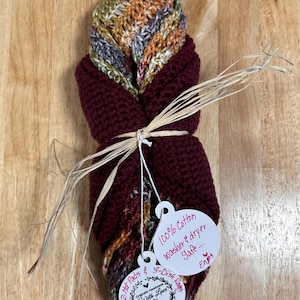 May include: A bundle of handmade crochet kitchen items, including two hot pads and three dish rags, tied with raffia. The items are a mix of burgundy and multicolored yarn. The tags read "100% Cotton washer & dryer safe..." and "Originally Handmade With Love By M.A."