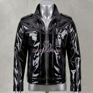 May include: A glossy black jacket with a high collar, multiple zippered pockets, and shoulder epaulets. The jacket is displayed on a mannequin and features a full-length zipper closure. The material has a shiny, patent leather appearance.