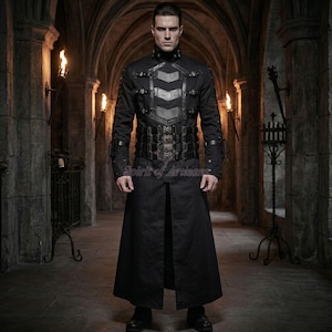 May include: A black long-sleeved coat featuring a high collar, a front panel with horizontal chevron-shaped leather-like straps, and a wide waist belt with multiple vertical straps and metallic buckles, extending to a floor-length hemline.