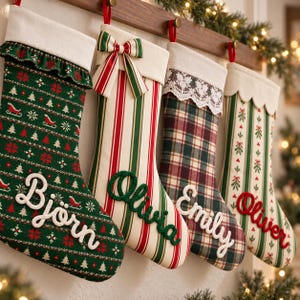 Könnte beinhalten: Vier Weihnachtssocken hängen in einer Reihe. Die erste ist grün mit einem rot-weißen Muster und dem Namen Björn. Die zweite ist cremefarben mit rot-grünen Streifen, einer Schleife und dem Namen Olivia. Die dritte ist kariert mit Spitze und dem Namen Emily. Die vierte ist gestreift mit Mistelzweigen und dem Namen Oliver.