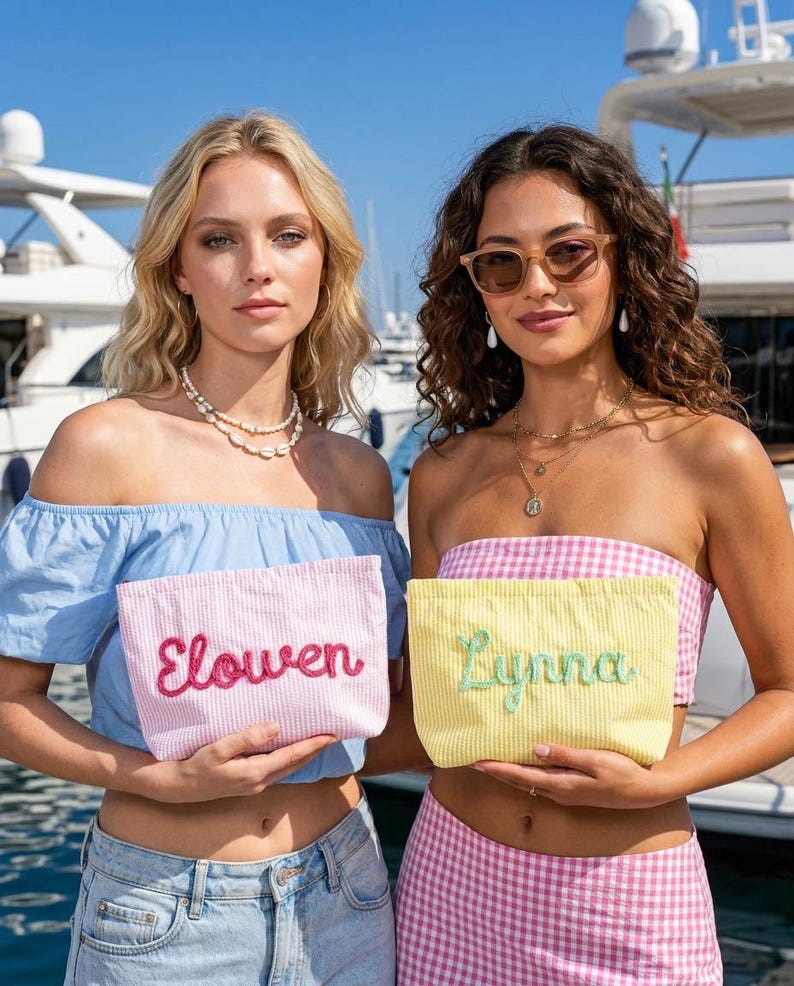 Puede incluir: Dos mujeres sostienen neceseres personalizados. Una bolsa es rosa con el nombre "Elowen" bordado en rojo, la otra es amarilla con "Lynna" en verde. Ambas bolsas tienen un patr&oacute;n de rayas.