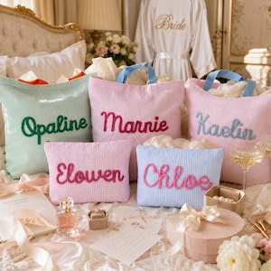 May include: Three large seersucker tote bags in mint, pink, and light pink with blue handles, featuring embroidered names Opaline, Marnie, and Kaelin. Two smaller matching pouches in pink and blue feature the embroidered names Elowen and Chloe.
