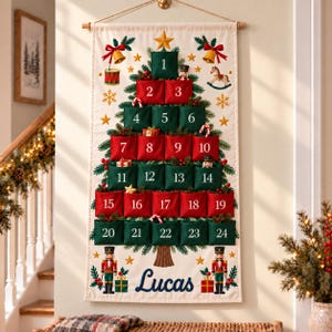 May include: A cream-colored fabric wall hanging featuring a Christmas tree design with twenty-four numbered pockets in red and green. The tree is decorated with nutcracker figures, bells, and stars. The name Lucas is printed in blue at the bottom.