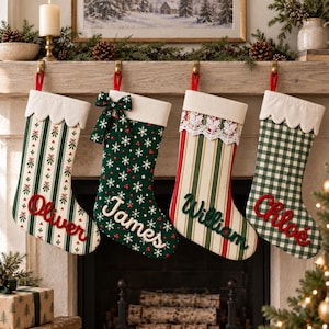 Puede incluir: Cuatro calcetines navideños personalizados colgados en fila. El primero presenta rayas verdes y muérdago con el nombre Oliver. El segundo es verde oscuro con copos de nieve y un lazo, etiquetado James. El tercero tiene rayas rojas y verdes con encaje, etiquetado William. El cuarto es de cuadros verdes y blancos con el nombre Chloe.