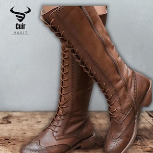May include: Brown leather knee-high boots with lace-up detailing and a side zipper. The boots feature brogue-style perforations on the toe and are displayed on a wooden surface. The brand logo "Cuir Vault" is visible in the upper left corner.