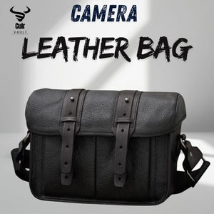 May include: Black leather camera bag with two buckle straps and a shoulder strap. The bag has the words "CAMERA LEATHER BAG" printed on the top. The bag is from the brand "Cuir Vault".