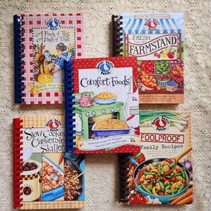 May include: Five spiral-bound Gooseberry Patch cookbooks featuring illustrated covers. Titles include A Pinch of This A Dash of That, Fresh from the Farmstand, Comfort Foods, Slow Cooker Casserole Skillet, and Foolproof Family Recipes with colorful food imagery.