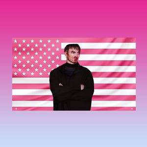 May include: A person with a bruised face stands in front of a pink American flag. The flag has white stars and pink stripes. The person is wearing a black jacket and a dark shirt.
