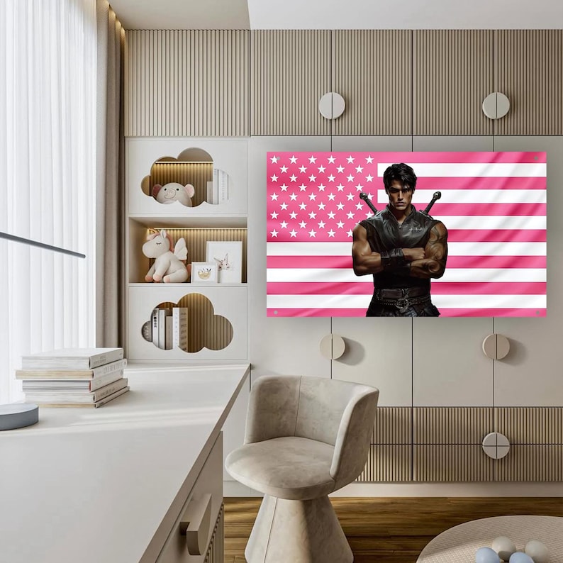 May include: A framed print featuring a muscular figure with crossed arms, set against a pink American flag. The artwork is displayed in a modern room with a white desk, cloud-shaped shelves, and a neutral-toned chair.