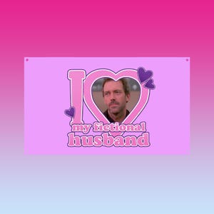 Può includere: Un cartello rettangolare rosa con la frase "I love my fictional husband". L'amore è rappresentato da una grande "I" rosa e un cuore con la foto di un uomo. Piccoli cuori viola accentuano il design.