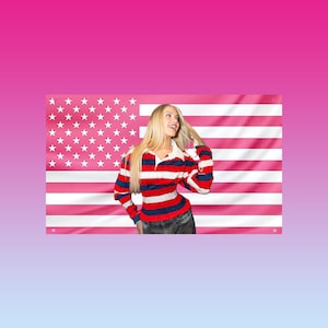 Puede incluir: Una mujer con una camiseta de rugby a rayas rojas, blancas y azules posa frente a una bandera estadounidense rosa. La camiseta tiene cuello blanco y mangas largas. La bandera tiene rayas blancas y estrellas rosas.