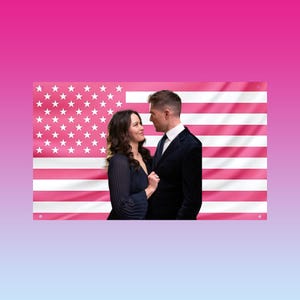 Pode incluir: Um casal está em frente a uma bandeira americana rosa. A mulher usa um vestido azul escuro, e o homem usa um terno escuro com camisa branca e gravata. O fundo tem um gradiente de rosa e azul.