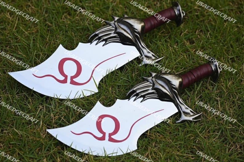 May include: Two decorative fantasy swords with silver-colored blades and handles wrapped in burgundy leather. The blades have a white surface with a red omega symbol. The swords are lying on a bed of green grass.