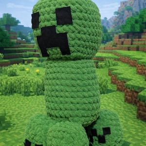 Pode incluir: Um grande Creeper de pelúcia verde do videogame Minecraft. O Creeper tem uma cabeça quadrada com olhos e boca quadrados pretos e um corpo cilíndrico. Está em uma superfície verde pixelada.