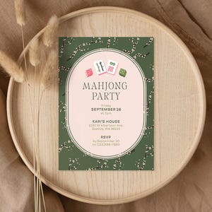 Könnte beinhalten: Eine Einladungskarte zur Mahjong-Party mit grünem floralem Hintergrund und einem ovalen Design. Das Oval zeigt Mahjong-Steine und die Worte "MAHJONG PARTY". Details: Datum, Uhrzeit, Ort und RSVP-Informationen.