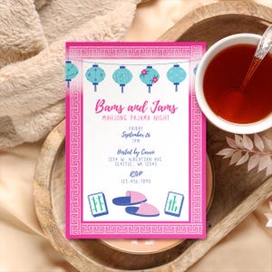 Könnte beinhalten: Eine rosa Einladungskarte mit dem Text "Bams and Jams Mahjong Pajama Night" und Details. Die Karte zeigt blaue Laternen, einen dekorativen Rand und Illustrationen von Mahjong-Steinen und Hausschuhen. Eine Tasse Tee steht auf einem Holztablett.