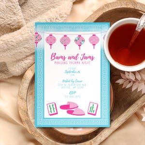 Könnte beinhalten: Eine türkisfarbene Einladung mit dem Text "Bams and Jams Mahjong Pajama Night" und rosa Laternenillustrationen. Die Einladung enthält Veranstaltungsdetails und RSVP-Informationen. Eine Tasse Tee mit einem Löffel befindet sich in der oberen rechten Ecke.