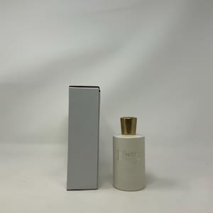 May include: A white perfume bottle with a gold cap and a matching rectangular box. The bottle has the text "Juliette Has A Gun" printed on it in a silver color. The box is a light gray color.