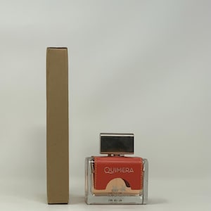 以下が含まれることがあります： 正方形の香水瓶と銀色のキャップ。ボトルには「QUIMERA」と印刷されたコーラル色のラベルが付いています。ボトルの隣には、背の高い長方形の段ボール箱があります。