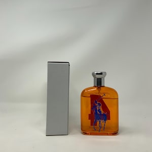 Könnte beinhalten: Eine orangefarbene Glasflasche mit silbernem Verschluss, mit einer blau-roten Grafik eines Polospielers und der Zahl 4. Daneben befindet sich eine passende rechteckige Schachtel.