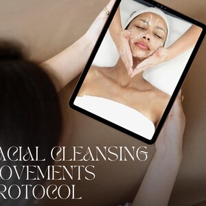 May include: A tablet screen shows a facial treatment in progress. The image depicts a person receiving a facial massage with cream applied. The text "FACIAL CLEANSING MOVEMENTS PROTOCOL" is at the bottom of the image.