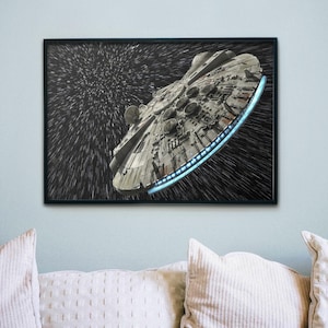 Puede incluir: Impresión enmarcada de la nave espacial Millennium Falcon en el espacio. La nave espacial está detallada con una combinación de colores gris y plateado, sobre un fondo negro con vetas de luz blanca. La impresión está en un marco negro.