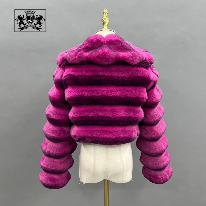 A mannequin wearing a vibrant pink fur coat with a distinctive hood.
