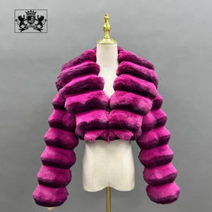 A mannequin wearing a vibrant pink fur coat with a distinctive collar design.