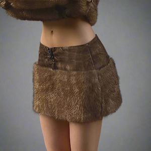 May include: A brown miniskirt with a fur trim. The skirt has a leather-like appearance with a decorative closure. The fur trim adds texture and warmth to the garment. The skirt is designed to be worn at the waist.