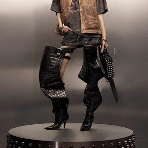 black, over-the-knee boots. Left boot has a crocodile texture with a buckle detail near the knee, and a stiletto heel. Right Boot is smooth black leather, slouching down, with a stiletto heel