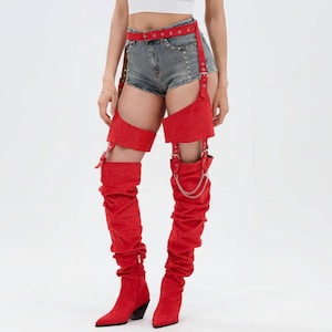May include: Red thigh-high boots with a pointed toe and a low heel. The boots are connected to a red belt and leg straps with silver hardware. The boots have a ruched design.