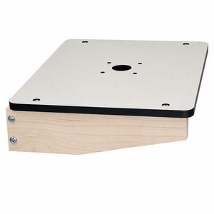 Puede incluir: Una plataforma de montaje rectangular con una superficie superior gris claro y borde negro, fijada a una base de madera clara. La placa superior incluye un orificio central circular rodeado por cuatro orificios pequeños y cuatro tornillos.