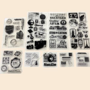 May include: Clear acrylic stamps with travel-themed designs. Includes stamps with text like "Road Trip," "Vacation," and "Smile," along with images of a camera, suitcase, and globe. Ideal for scrapbooking and crafting.