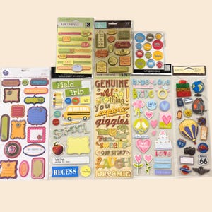 May include: A collection of decorative stickers in various shapes and sizes. The stickers feature phrases like "Joy," "Friends," and "Love," along with images of a school bus, hearts, and travel-themed elements. The color palette includes yellow, green, blue, and pink.